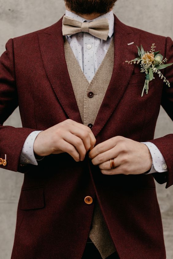 a chic groom's look with a burgundy woolen suit, a beige waistcoat, a polka dot shirt and a tan bow tie
