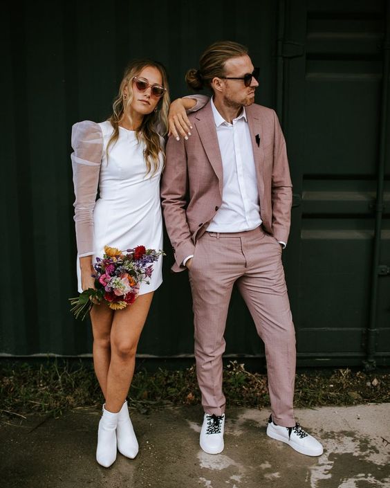 a chic modern groom's look with a mauve pantsuit, white sneakers, a white shirt are a cool combo with an unusual touch of color