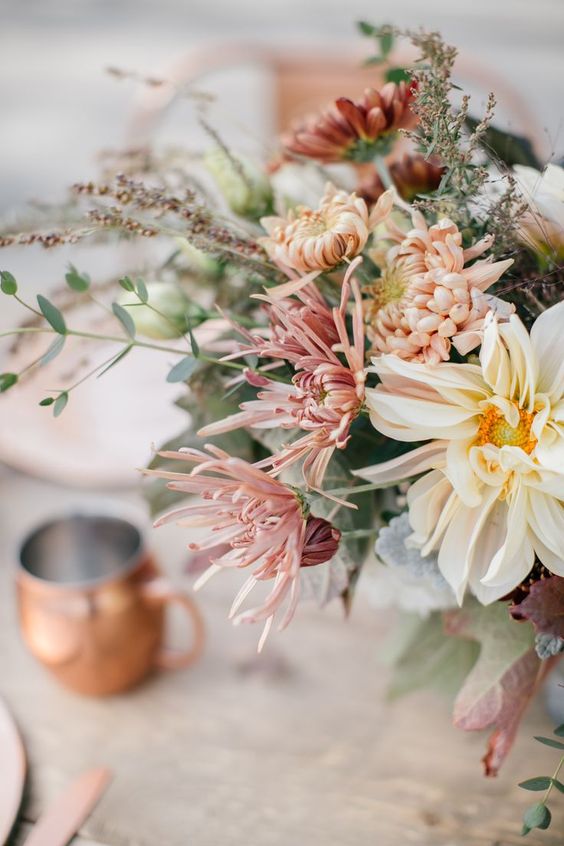 a chic wedding centerpiece of white, blush and light pink blooms including dahlias and mums and some greenery