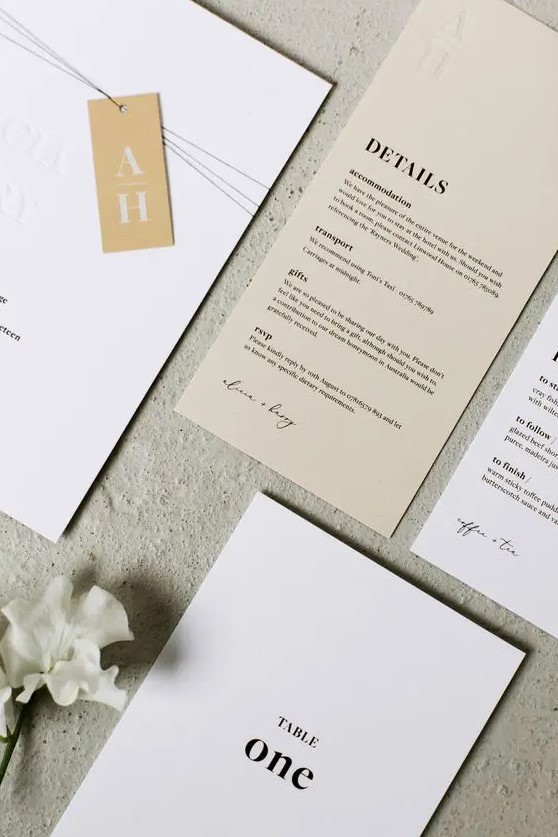 a chic white and tan wedding invitaiton suite with black letters and monogram tags is a cool idea for a minimalist wedding, and with plenty of detail
