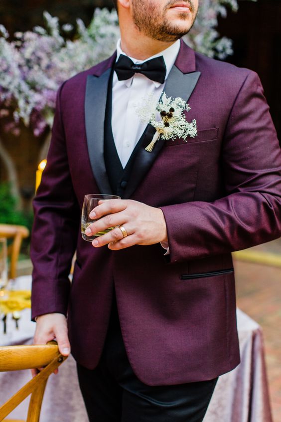 a classic groom's look with a purple tux, black lapels, a black waistcoat, and a black bow tie