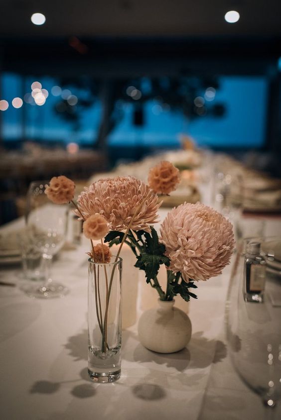 a cluster wedding centerpiece of blush chrysanthemums and seed pods plus some greenery is cute and chic