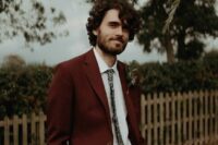 a cool fall groom’s look with a white shirt, a burgundy pantsuit, a floral print tie is ideal for a boho wedding