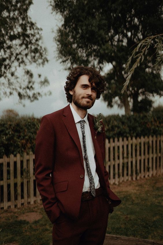 a cool fall groom's look with a white shirt, a burgundy pantsuit, a floral print tie is ideal for a boho wedding