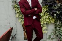 a deep red suit, a white shirt, black shoes with no socks for a bold and chic modern groom’s look