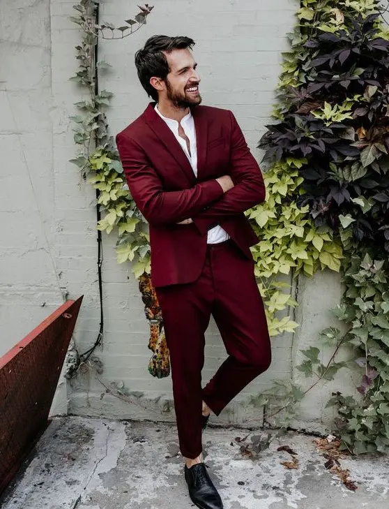 a deep red suit, a white shirt, black shoes with no socks for a bold and chic modern groom's look
