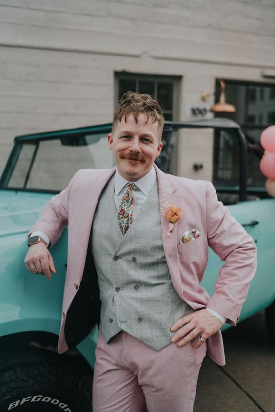 a delicate and whimsy groom's look with a blush pantsuit, a grey waistcoat, a white shirt, a bright floral tie and a handkerchief