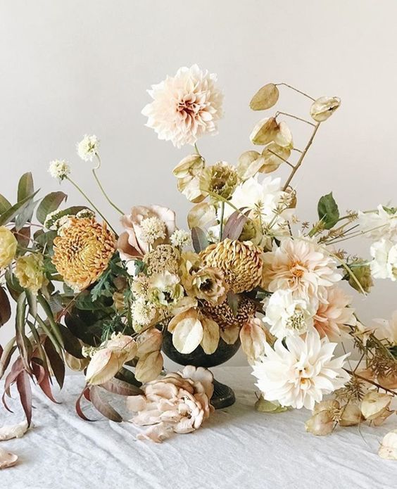 a dreamy wedding centerpiece of white and blush dahlias, yellow mums and greenery is a romantic idea