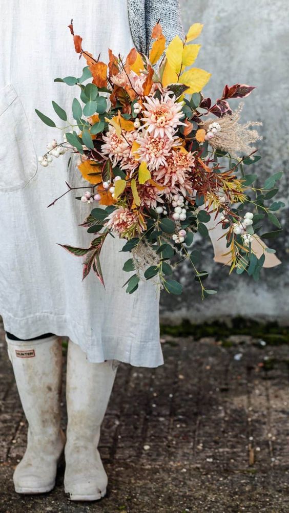 a fall wedding bouquet of pink chrysanthemums, greenery, bold fall foliage and berries is a fun and bright idea