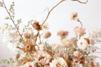 a fine art wedding centerpiece of white and blush roses, rust chrysanthemums, some blush and white fillers and greenery