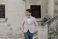 a gorgeous groom’s look with graphite grey pants and a bow tie, a white shirt, a pink jacket and neutral shoes