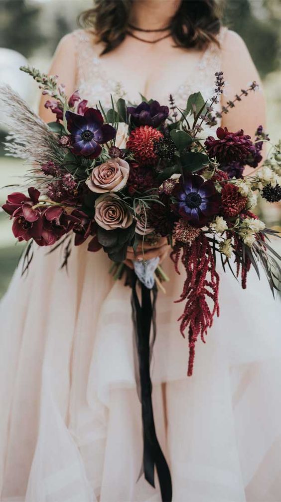 a jaw-dropping dark wedding bouquet of mauve roses, burgundy orchids and anemones, deep purple chrysanthemums and greenery and grasses