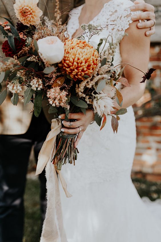 a lovely autumnal wedding bouquet of blush peony roses, rust dahlias and chrysanthemums, grasses and greenery is chic