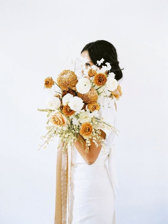 a lovely fall wedding bouquet of white and rust roses, chrysanthemums, blooming branches and some swet peas blooms