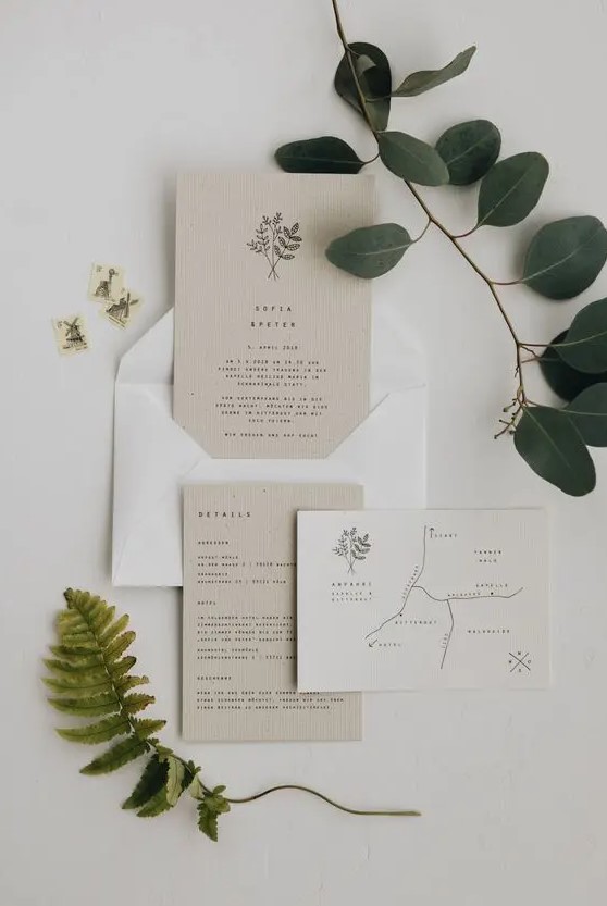 a lovely tan and white minimalist wedding invitation suite with small black lettering, a printed map and botanical prints and patterns