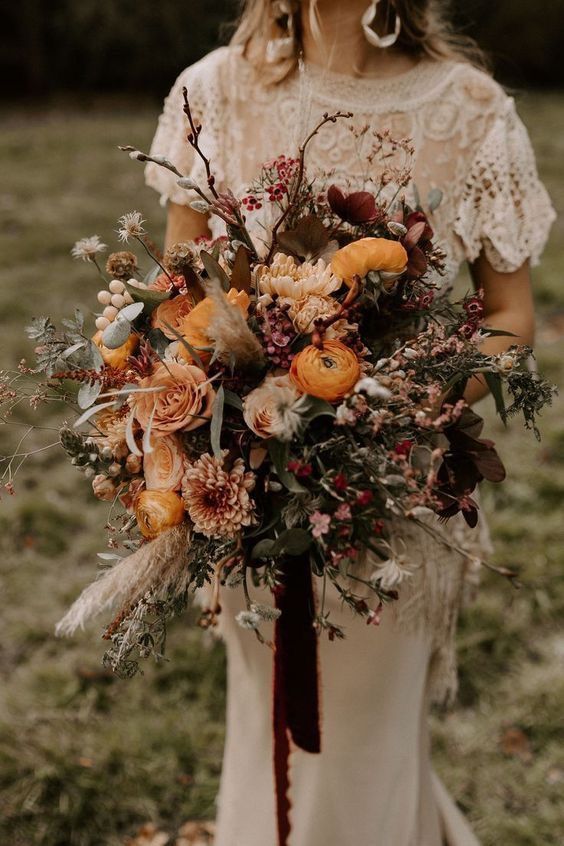 a lusha nd dimensional wedding bouquet with yellow ranunculus, yellow and blush roses, chrysanthemums, berries, grasses, twigs