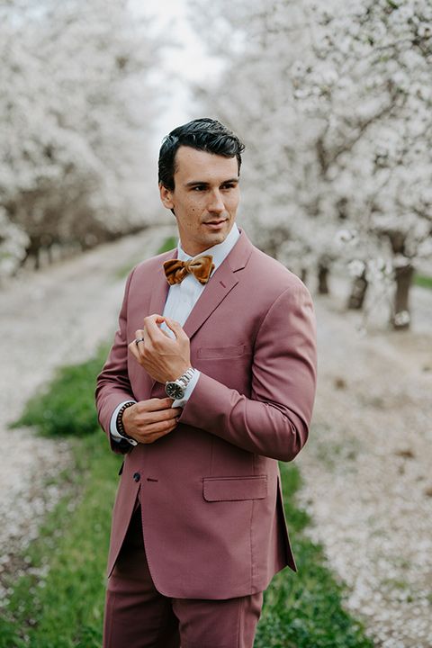 a mauve to pink pantsuit, a white shirt, a rust-colored velvet bow tie are a great combo for a lovely spring groom's look