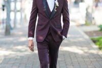 a modern groom’s look with a purple tuxedo with black lapels, a waistcoat, black shoes and a black bow tie