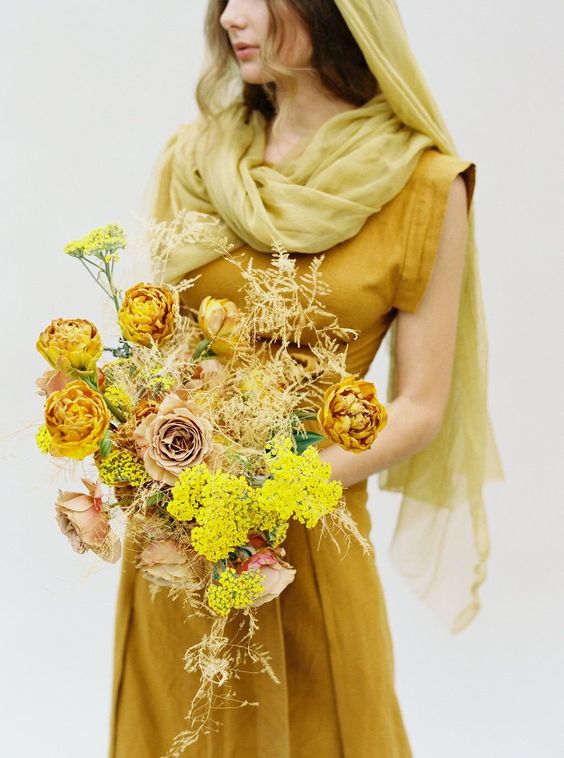a monochromatic mustard wedding bouquet of roses, chrysanthemums, mimosa, greenery and dried leaves for the fall