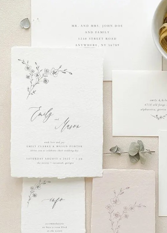 a neutral handmade paper wedding invitation suite with black calligraphy and botanical prints is a cool idea for spring