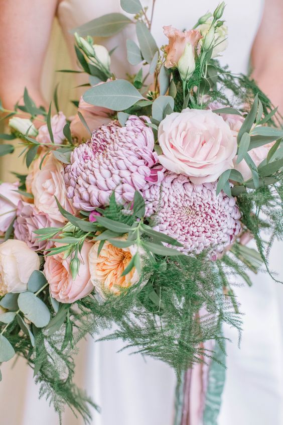 a pastel wedding bouquet of pink and blush peony roses, light pink chrysanthemums, roses and greenery