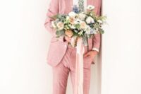a pink pantsuit, a white shirt, black shoes and checked socks, a floral tie compsoe a whimsical look for the groom