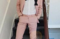 a pink suit, a white shirt, black shoes and a black bow tie for a fresh and cool summer groom’s outfit
