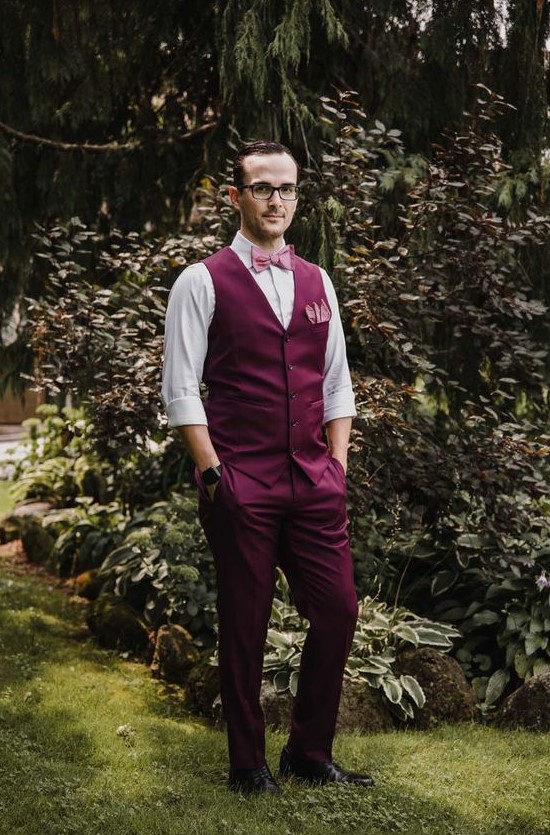 a purple suit with a waistcoat, a white shirt and a pink bow tie for a whimsical and statement groom's look