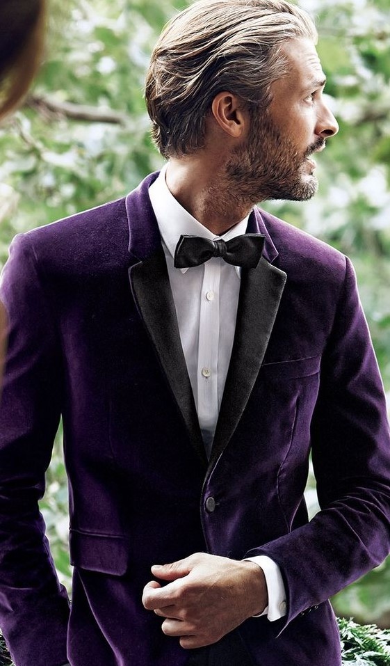 a purple velvet tux with black lapels is a refined and chic groom's outfit idea