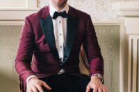 a refined look with a burgundy blazer with black lapels, black pants, a black bow tie and a white shirt with black buttons