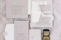 a refined minimalist wedding invitation suite in grey and white, with black lettering and white ribbons and stamps is cool