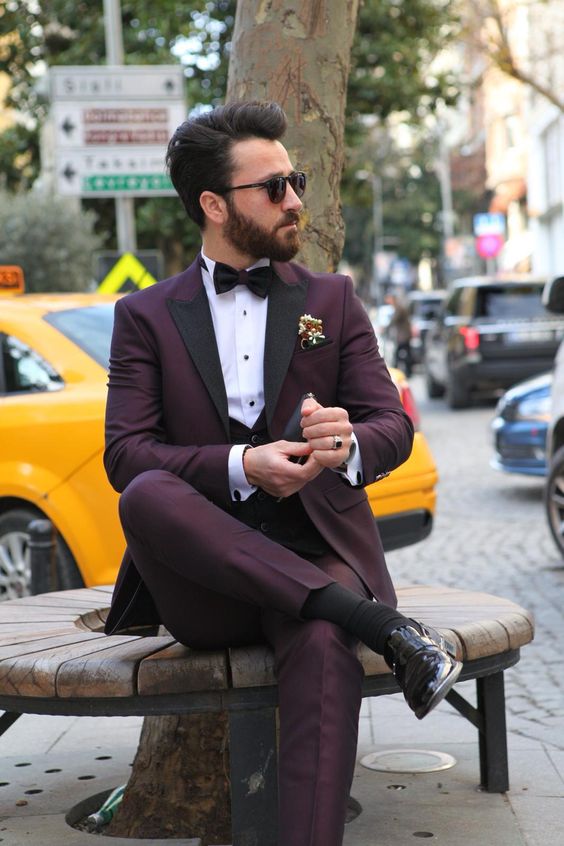 a refined purple groom's outfit with a tuxedo and black lapels, a waistcoat, black shoes and socks, a black bow tie