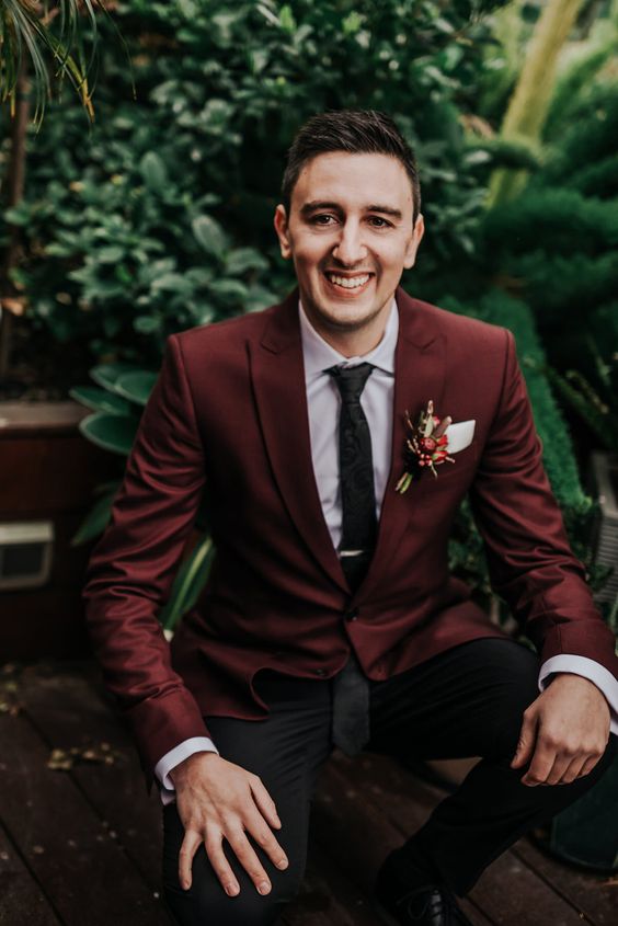 a simple and modern groom's outfit with black trousers, a burgundy blazer, a white shirt, a black tie for the fall