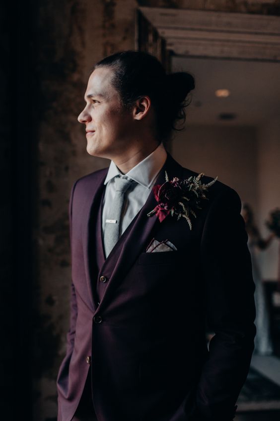 a stylish purple three-piece groom's suit, a neutral shirt, a light grey tie and a bold boutonniere for the fall