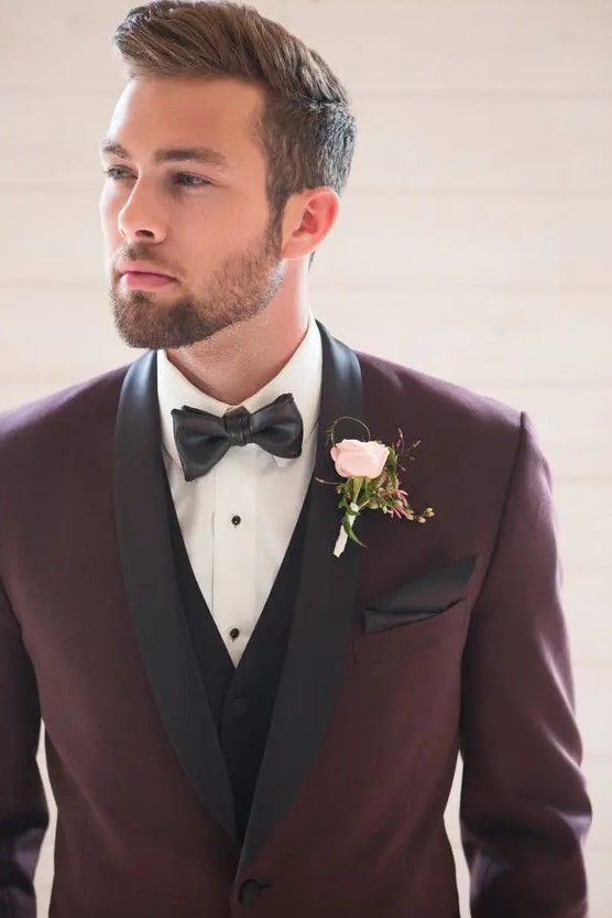 a stylish take on a tuxedo look - a burgundy tux with black lapels and a black vest