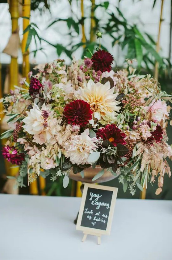 a super lush wedding arrangement of neutral and burgundy blooms, eucalyptus and some foliage for a summer or fall wedding