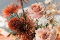 a unique wedding centerpiece of blush roses, rust dahlias and chrysanthemums, white daisies and berries