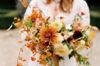 a vibrant wedding bouquet of rust and white dahlias and chrysanthemums, greenery, berries and fall leaves is amazing