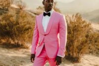 an edgy groom’s look with a hot pink tuxedo, a white shirt and a black bow tie, black printed loafers just wows