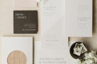 an ethereal neutral wedding invitation suite with a dark envelope, a bit of wood and some color blocking