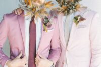 grooms wearing a blush and a light pink pantsuit, a neutral and purple tie and feather-embellished beards