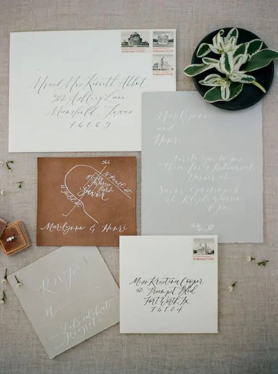 neutral wedding invitation suite with calligraphy and a map painted on a piece of leather