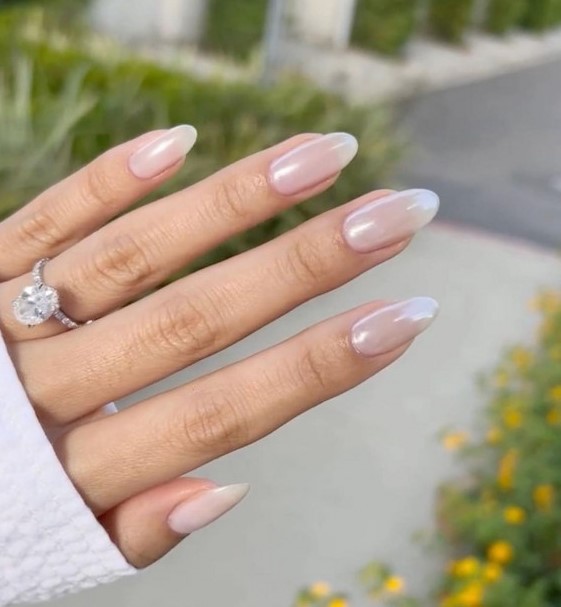 very subtle and delicate blush chrome nails of an almond shape are a cool solution for a bride, they look very soft