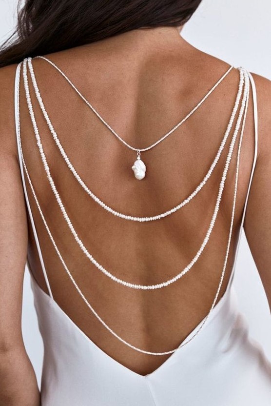 a layered back necklace of small pearls plus a large baroque one to highlight the open back of the wedding dress