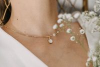 a modern bridal necklace of gold, with a large moonstone is a catchy idea for a modern bride wearign a plainw edding dress