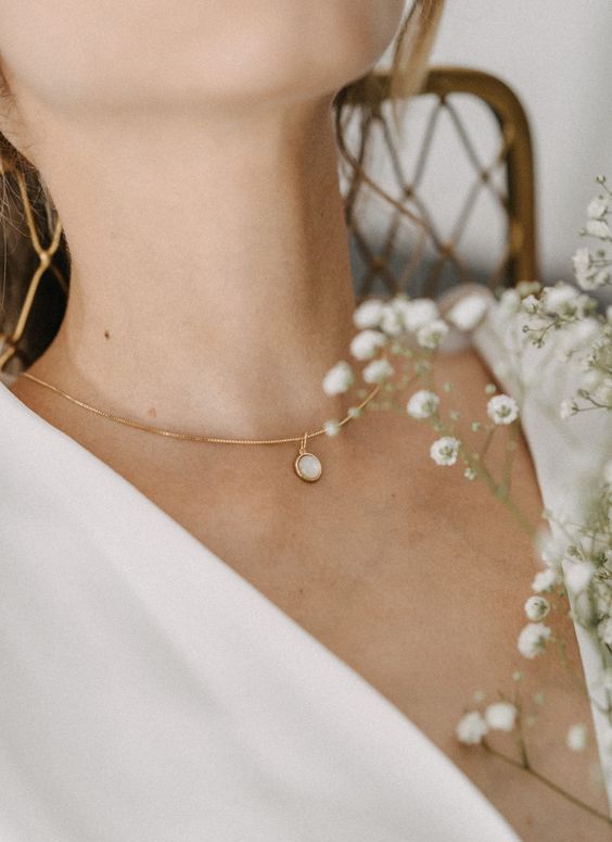 a modern bridal necklace of gold, with a large moonstone is a catchy idea for a modern bride wearign a plainw edding dress