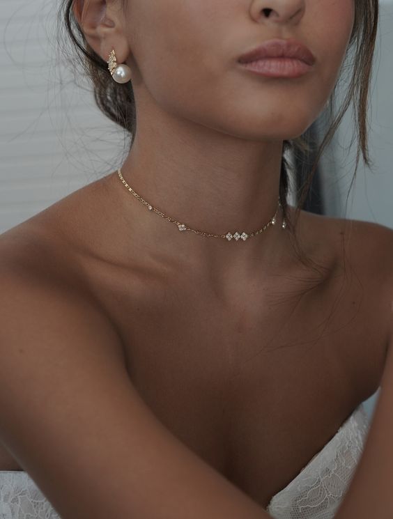 a small delicate choket with some rhinestones and statement pearl earrings for a catchy modern bridal look