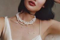 a trendy bridal look with a silk wedding dress with straps and a statement pearl necklace with pearl pendants is a cool idea