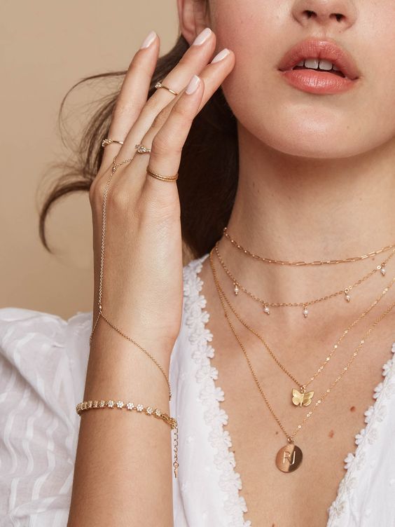 layered dainty gold necklaces, with a butterfly, a coin and small pearls will raise your bridal look to a new level