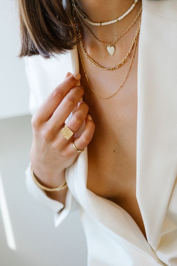layered gold necklaces and a small bead choker are a bold solution for a modern bridal look with a pantsuit